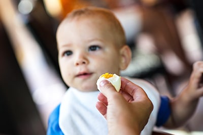 Mum feeding baby boiled egg
