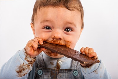 A baby boy eating a block of chocolate