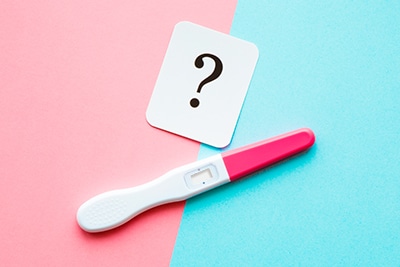 Pregnancy test on pastel blue and pink background