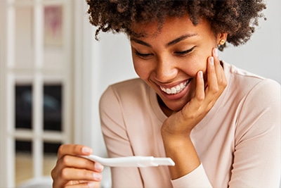 happy woman holding a positive pregnancy test