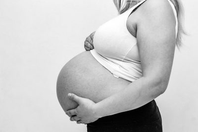 Black and white photo of a pregnant woman holding her stomach.
