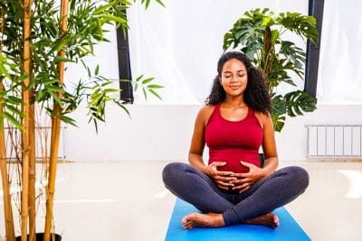 Reflection of a pregnant woman in a standing yoga pose.