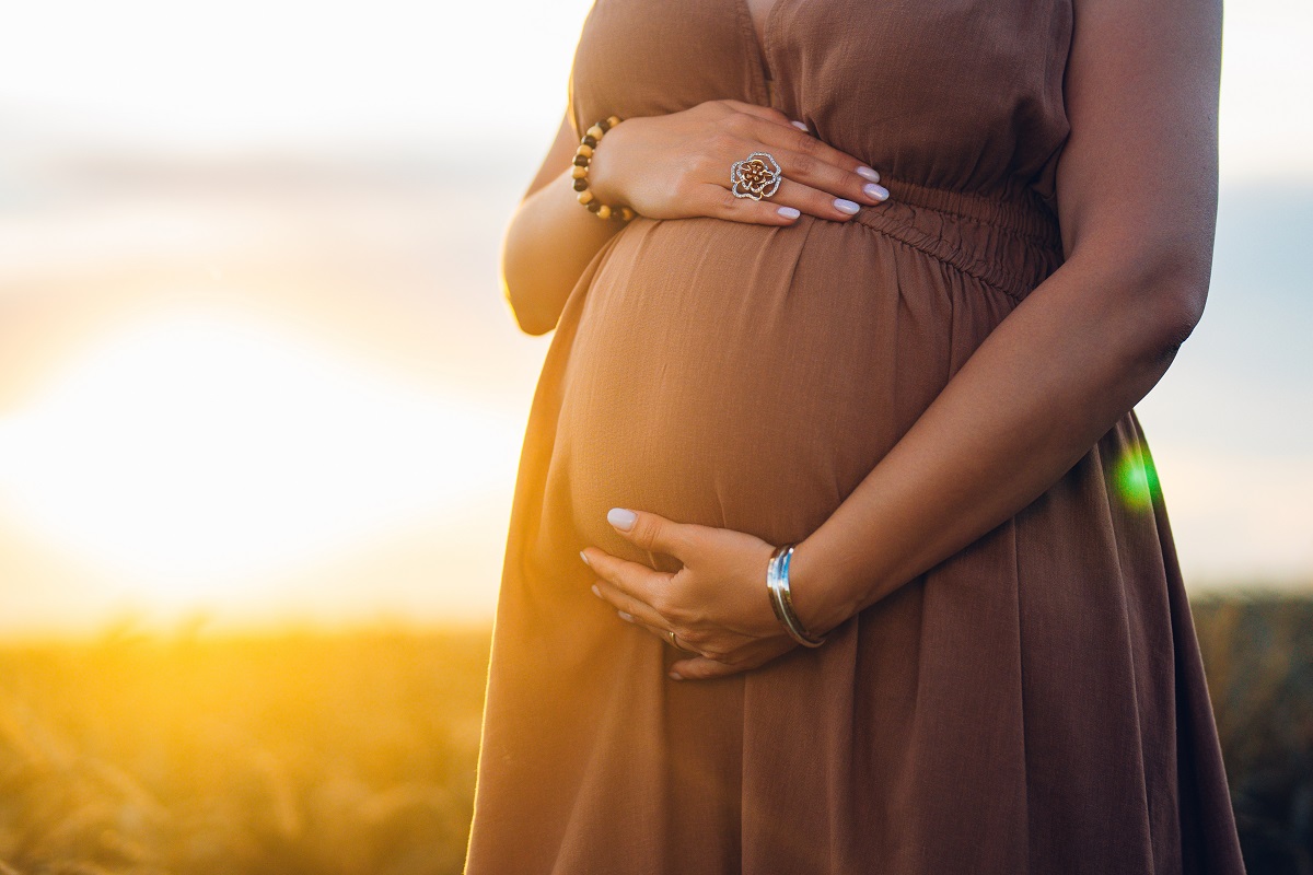 A close-up of a pregnant woman's belly as she gently cradles it with both hands